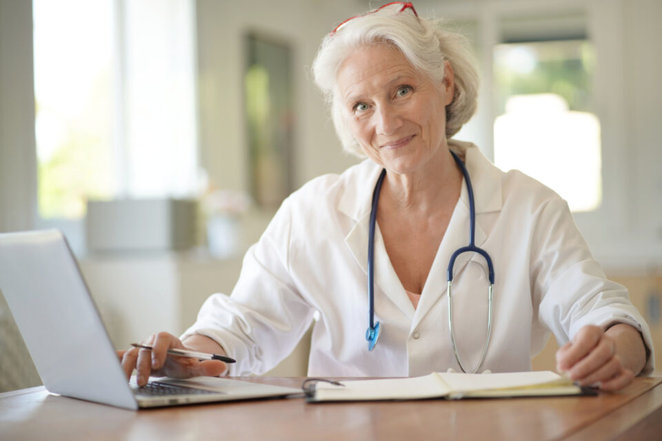 Portrait,Of,Smiling,Senior,Woman,Doctor,With,White,Hair,,Working