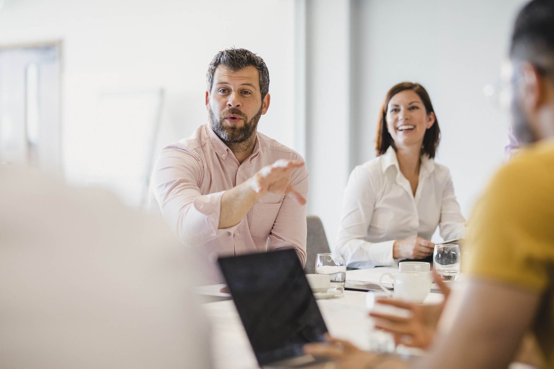 Businessman with beard explaining in meeting with colleagues